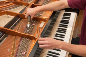 Piano technician adjusting piano action regulation